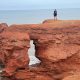 Taking the Long Way, hiker on red cliff looking out at ocean